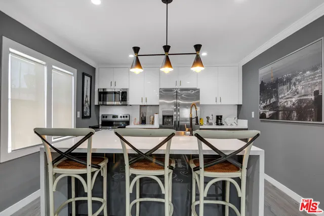 a kitchen with stainless steel appliances kitchen island granite countertop a sink a stove a refrigerator cabinets and chairs