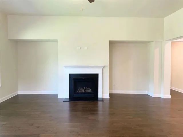 a view of an empty room with wooden floor and a fireplace