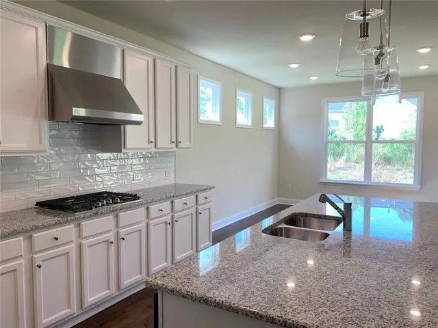 a kitchen with granite countertop a sink a stove and cabinets