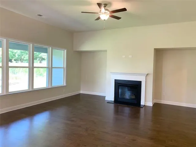 an empty room with wooden floor a fireplace and windows