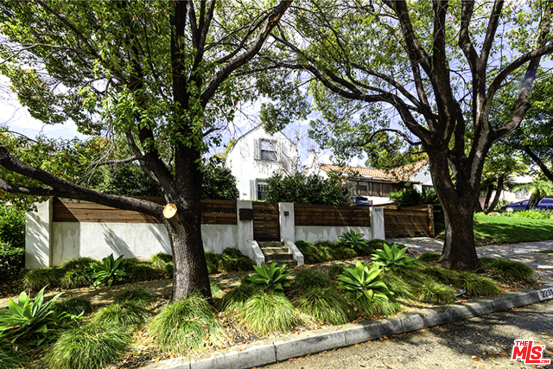 a backyard of a house with table and chairs and a large tree