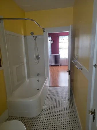 an empty room with wooden floor and hallway