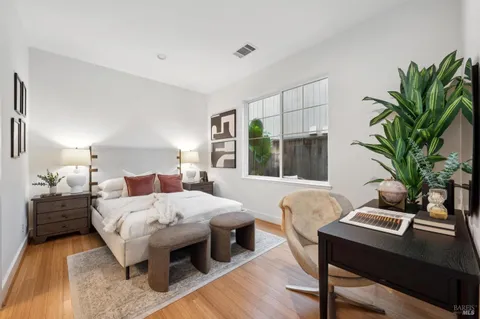 a bedroom with a bed table chair and a potted plant