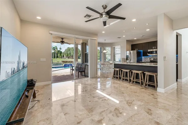a living room with stainless steel appliances furniture a chandelier open kitchen view