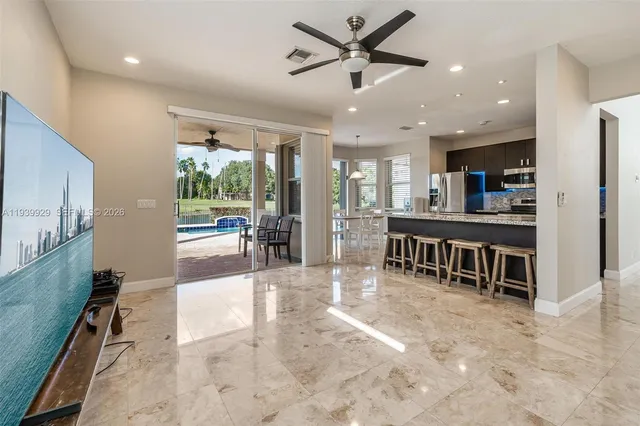 a living room with stainless steel appliances furniture a chandelier open kitchen view