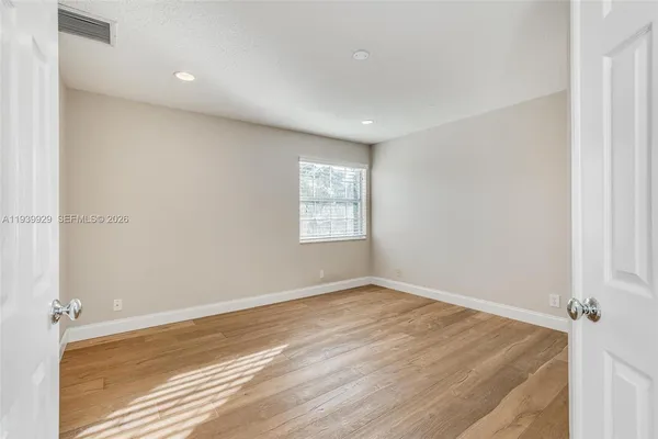 a view of an empty room with wooden floor and a window