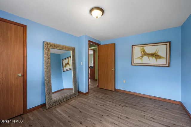 a view of an empty room with wooden floor and closet