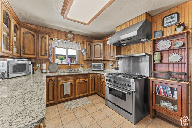 6407 North Dry Frk Cyn Road West Vernal, UT 84078 - Photo 25 of 48 Kitchen with island exhaust hood, appliances with stainless steel finishes, brown cabinets, a sink, and wood walls