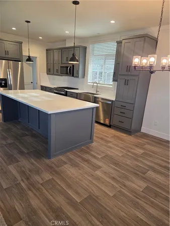 a large kitchen with stainless steel appliances a large counter top a stove a chimney a sink and a large window