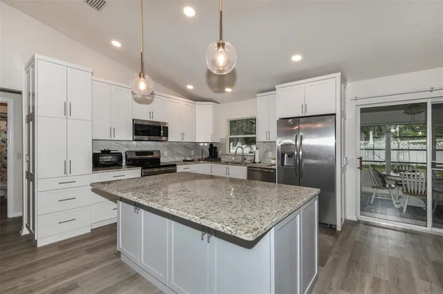 a kitchen with stainless steel appliances granite countertop a sink a stove and a refrigerator