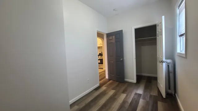 a view of an empty room with closet and a window