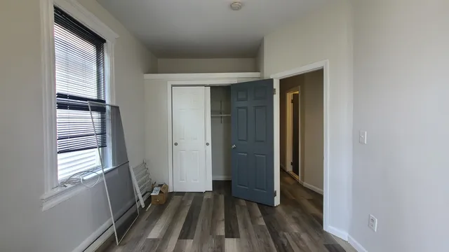 a view of hallway with window and wooden floor