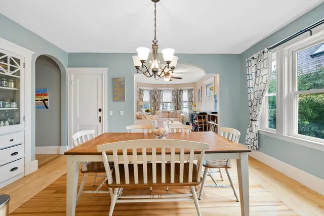 a dining room with wooden floor a chandelier a wooden table and chairs