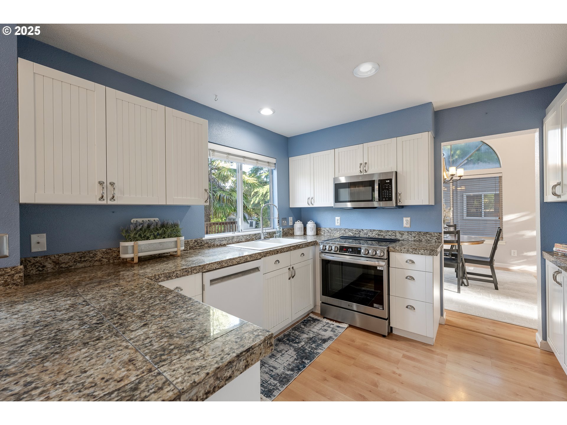 11450 Southwest Pintail Loop Beaverton, OR 97007 - Photo 6 of 35 a kitchen with stainless steel appliances granite countertop a stove top oven a sink a dining table and chairs