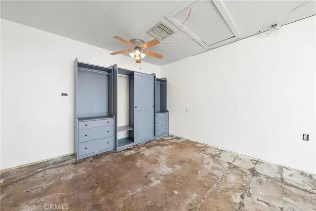an empty room with windows and ceiling fan