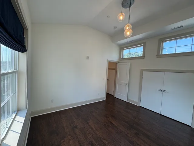 an empty room with wooden floor cabinet and windows