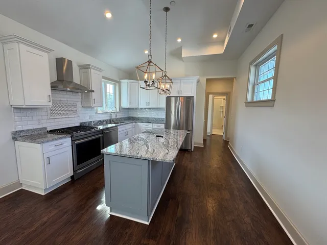 a kitchen with stainless steel appliances granite countertop wooden floors and white cabinets