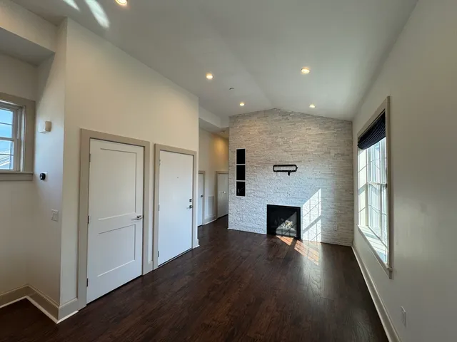 an empty room with wooden floor fireplace and windows