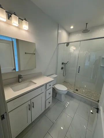a bathroom with a granite countertop sink a toilet and a shower