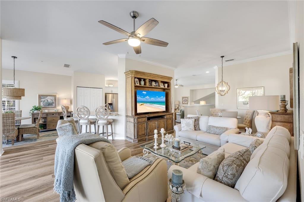 6879 Redbay Park Road, Unit 203 Naples, FL 34109 - Photo 14 of 43 Living area with wood finished floors, ornamental molding, a chandelier, and ceiling fan