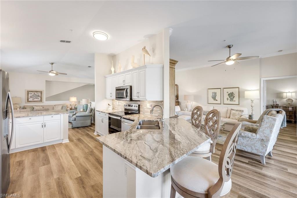 6879 Redbay Park Road, Unit 203 Naples, FL 34109 - Photo 43 of 43 Kitchen with open floor plan, a ceiling fan, a peninsula, a breakfast bar area, and light stone counters