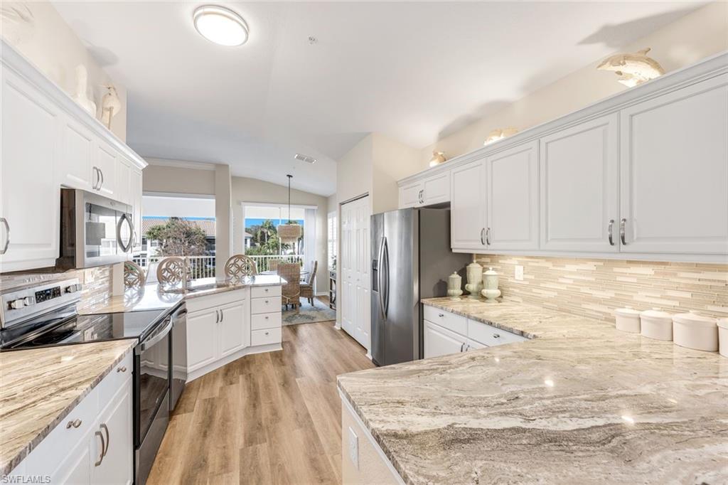 6879 Redbay Park Road, Unit 203 Naples, FL 34109 - Photo 18 of 43 Kitchen with stainless steel appliances, white cabinetry, vaulted ceiling, a peninsula, and pendant lighting