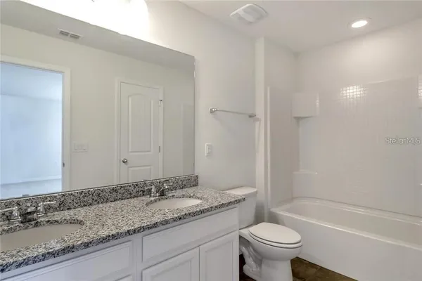 a bathroom with a granite countertop sink a toilet and a bathtub