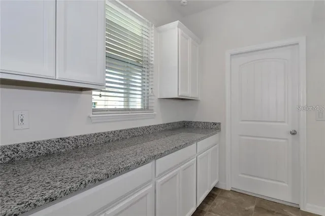 a kitchen with granite countertop white cabinets and a window