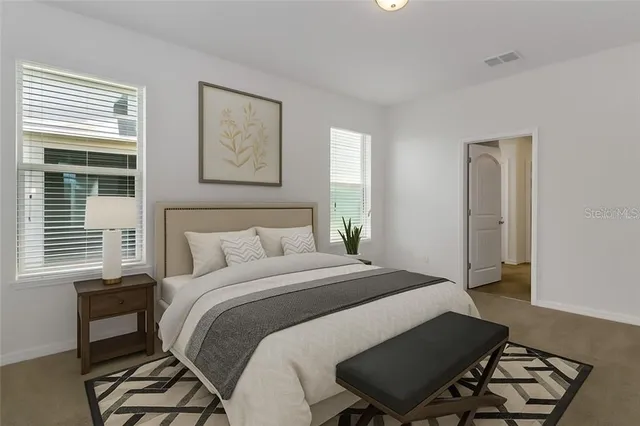 a bedroom with a bed two windows and a chair