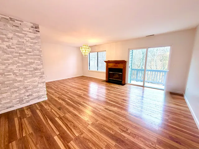 a view of empty room with wooden floor and fireplace