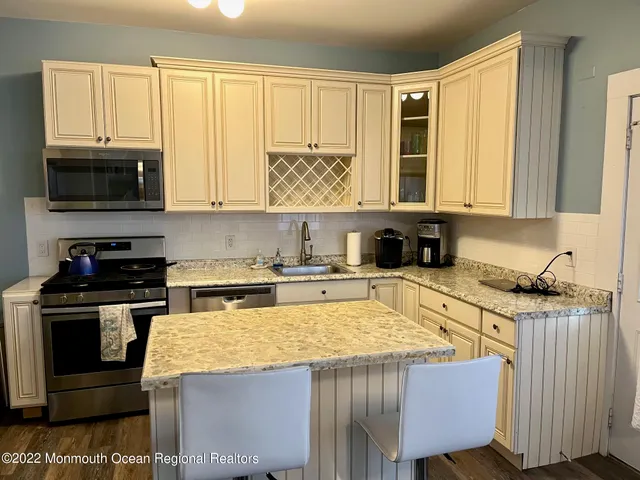 a kitchen with granite countertop a stove a sink and a microwave
