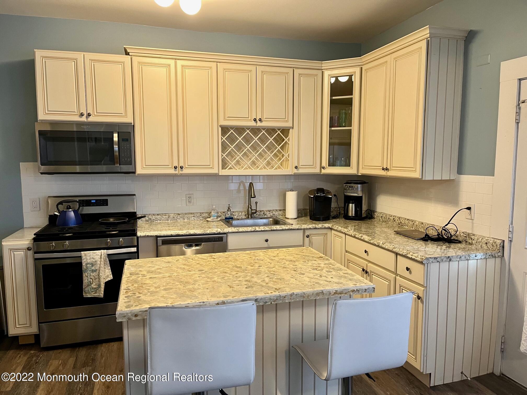 216 Main Street, Unit UP Avon-by-the-Sea, NJ 07717 - Photo 3 of 20 a kitchen with granite countertop a stove a sink and a microwave
