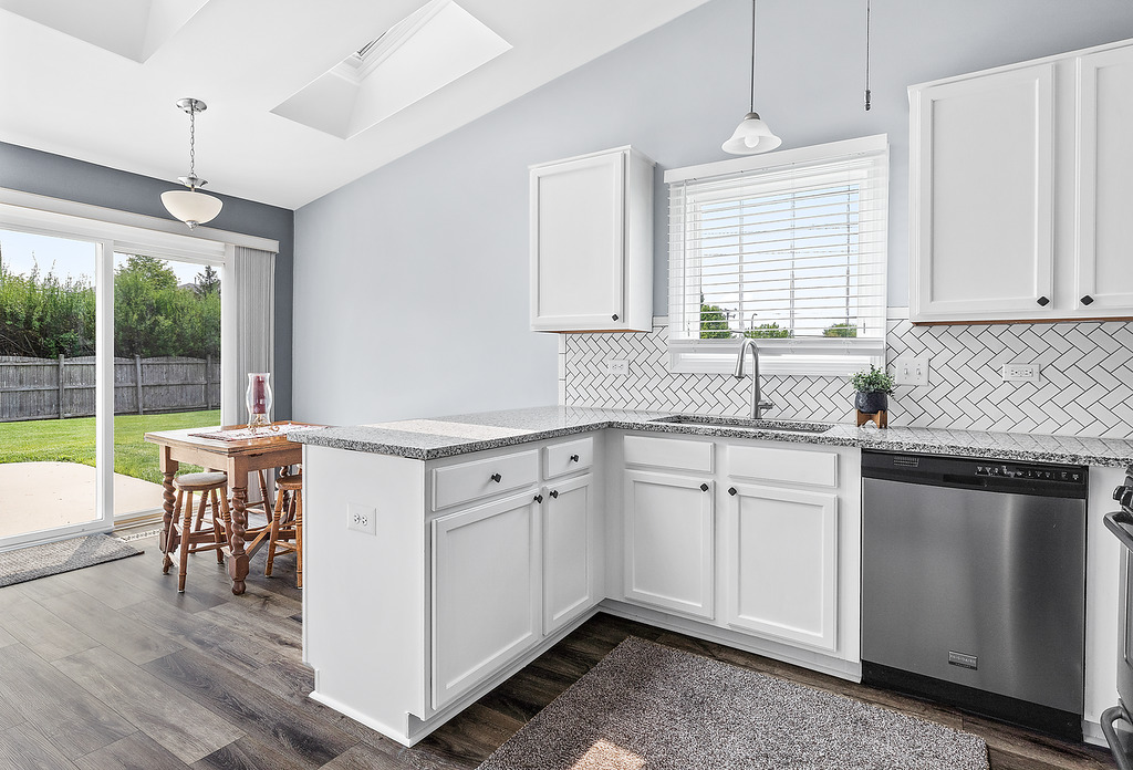 126 Dickens Trail Elgin, IL 60120 - Photo 7 of 23 a kitchen with kitchen island granite countertop a stove a sink a dining table and chairs with wooden floor