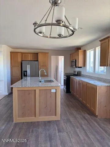 a large kitchen with stainless steel appliances granite countertop a stove a sink dishwasher and a refrigerator with wooden floor