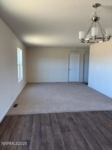an empty room with a chandelier fan and windows