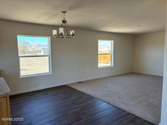 an empty room with wooden floor chandelier and windows