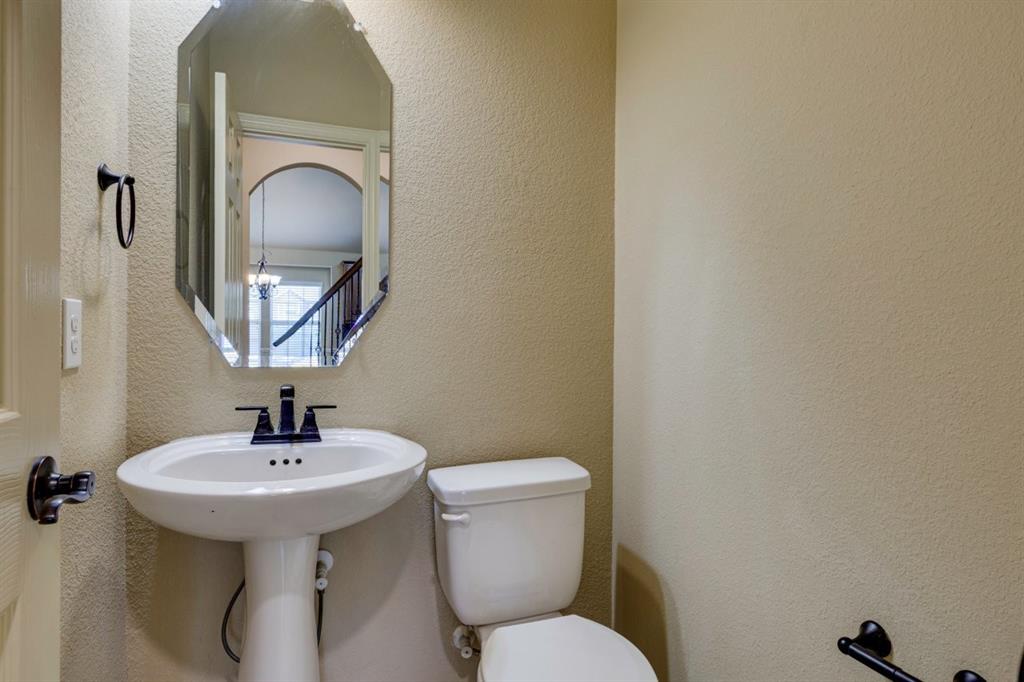 1522 Blue Jay Road Garland, TX 75043 - Photo 23 of 32 Pedestal sink with a matte black faucet, an octagonal wall-mounted mirror, and neutral-toned textured walls