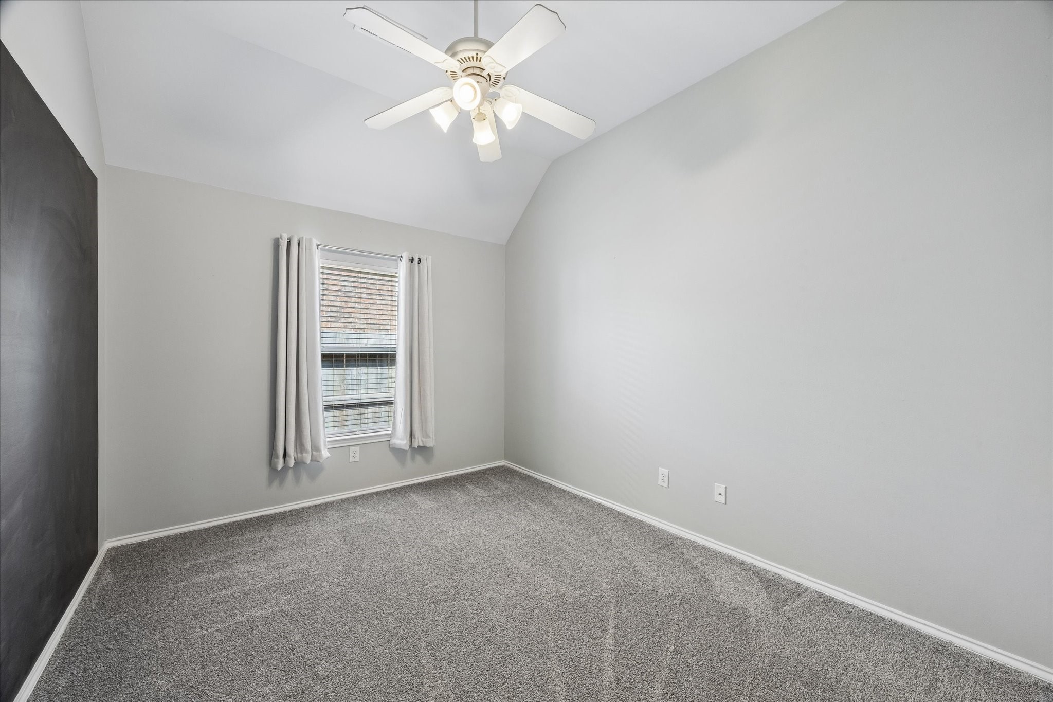 3118 Valley Court Manvel, TX 77578 - Photo 17 of 38 This room features neutral gray walls, a ceiling fan, and a window with white curtains. The space is carpeted, offering a cozy atmosphere, and is well-lit, perfect for a bedroom or office.