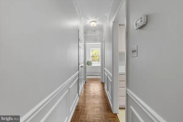 a view of a hallway with wooden floor and a bathroom