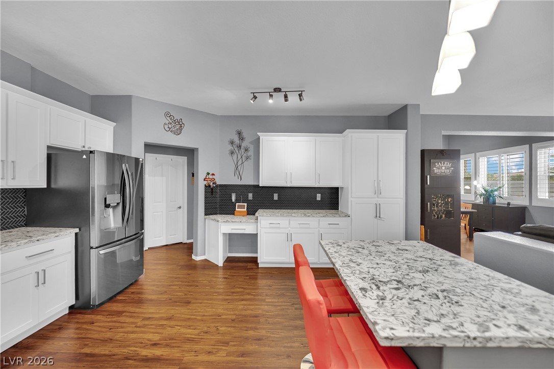 1724 Millstream Way Henderson, NV 89074 - Photo 18 of 60 White cabinetry, quartz counters, and rich wood flooring create a functional, inviting kitchen space.