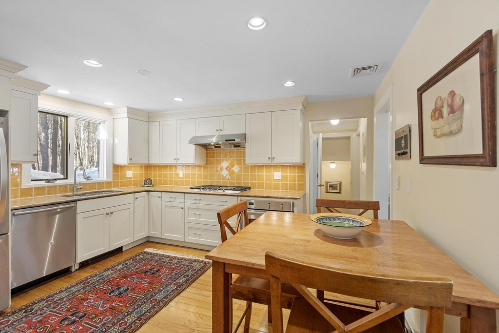 265 College Road Concord, MA 01742 - Photo 16 of 42 a kitchen with stainless steel appliances granite countertop a dining table chairs sink and wooden floor