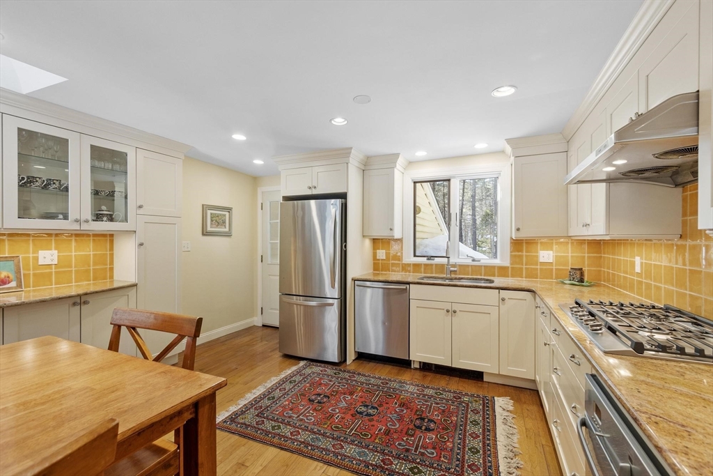 265 College Road Concord, MA 01742 - Photo 17 of 42 a kitchen with stainless steel appliances granite countertop a stove top oven a sink a dining table and chairs