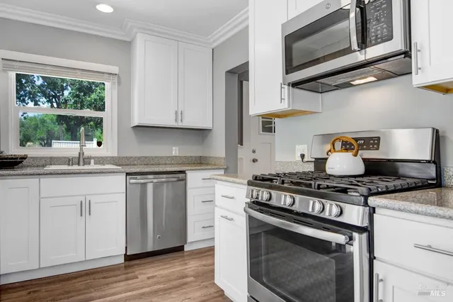 a kitchen with stainless steel appliances granite countertop a stove and a wooden floors