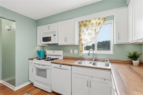 a kitchen with stainless steel appliances a white stove top oven and white cabinets