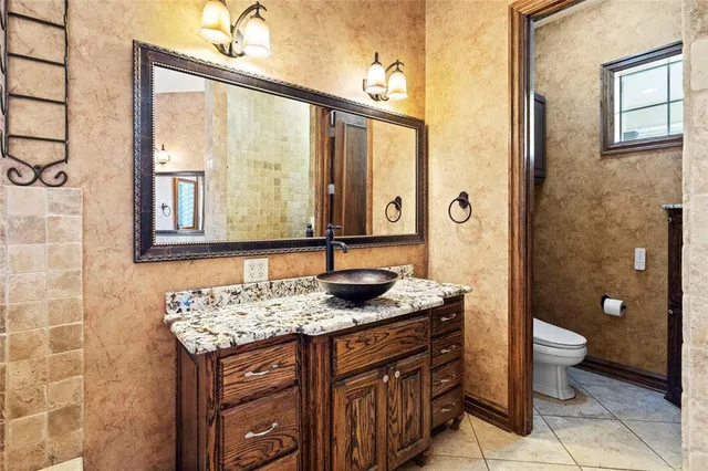 a bathroom with a granite countertop sink a toilet and a mirror