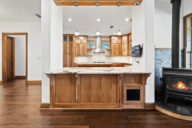 a kitchen with kitchen island granite countertop a stove and a fireplace
