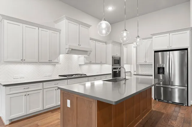 a kitchen with kitchen island a counter space a sink appliances and cabinets