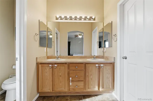 a bathroom with a granite countertop sink a toilet and a mirror
