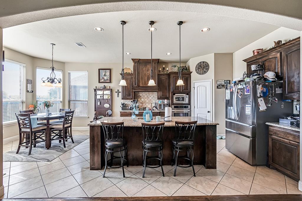 3206 Meadow Ridge Drive Midlothian, TX 76065 - Photo 23 of 37 a kitchen with stainless steel appliances kitchen island granite countertop a table chairs and a refrigerator