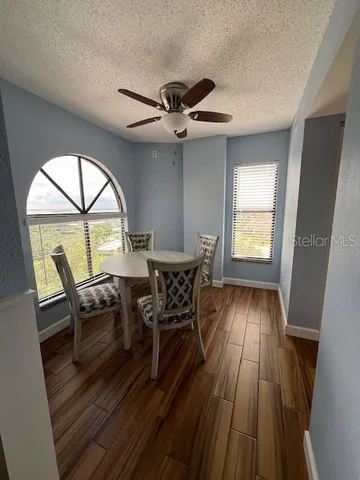 a dining room with wooden floor a chandelier fan a wooden table and chairs
